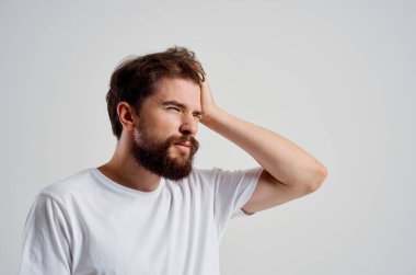 Beyaz tişörtlü bir adamın baş ağrısı, migren sorunları, izole edilmiş bir arka plan.