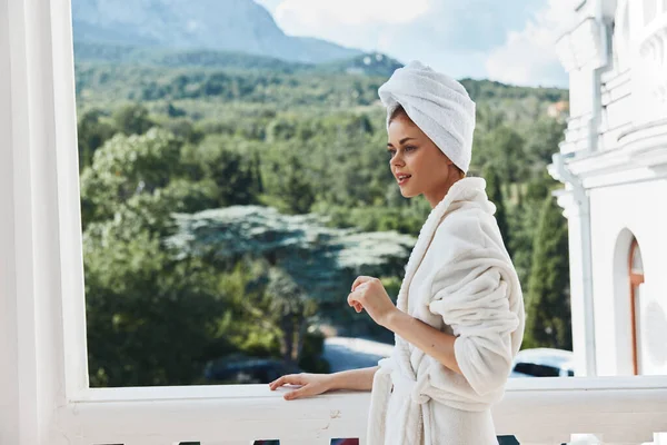 Güzel bir kadın, balkon mimarisinde dağların arka planında poz veriyor. Rahatlama konsepti.