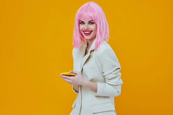 Woman with a phone in her hands pink hair studio yellow background — Stock Photo, Image