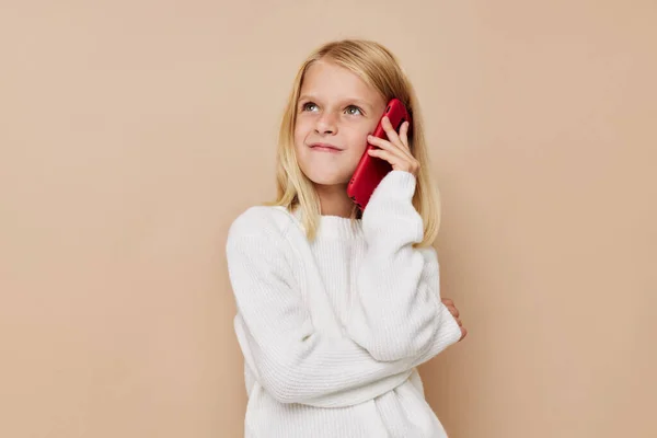 Portrét usmívajícího se malého roztomilého červeného telefonu v ruce na béžovém pozadí — Stock fotografie