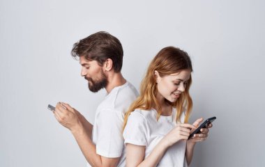 Beyaz tişörtlü erkek ve kadın ellerinde telefonlar stüdyo yaşam tarzı