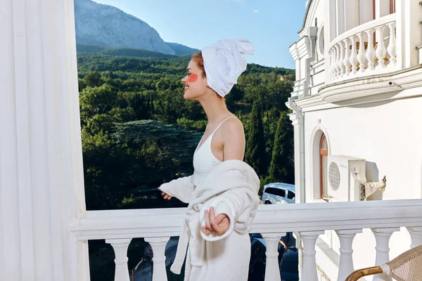 Donna in accappatoio in accappatoio bianco il balcone si affaccia sulle montagne concetto di relax — Foto Stock