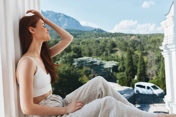 매혹적 인 젊은 여자 가 발코니에 앉아 아름다운 산을 바라보며 완벽 한 여름 햇살이 내리는 아침을 맞이 한다 — 스톡 사진
