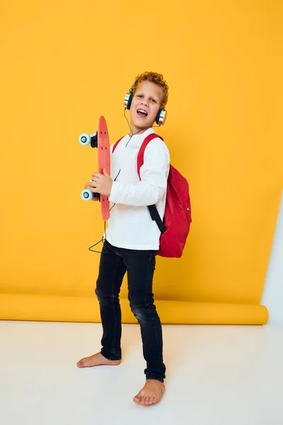 Adolescente skate vermelho fone de ouvido entretenimento fundo amarelo — Fotografia de Stock