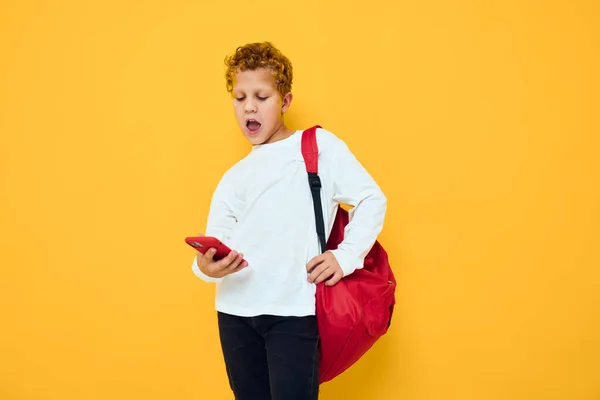 十代の男の子で白いスウェットシャツ携帯電話赤バックパック隔離された背景 — ストック写真