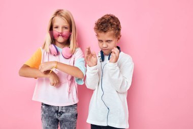 Pembe arka plan pozu veren kulaklık takan küçük bir çocuk ve kız.