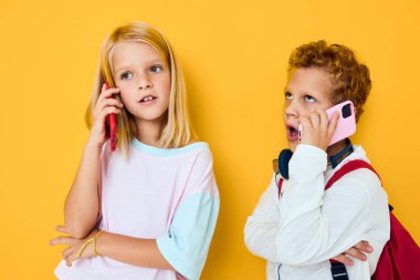 Hoş çocuklar telefon eğlence merkezi sarı arka planına bakıyor.