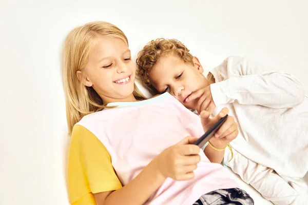 Fröhliche Mädchen und Jungen mit einem Handy in den Händen heller Hintergrund — Stockfoto