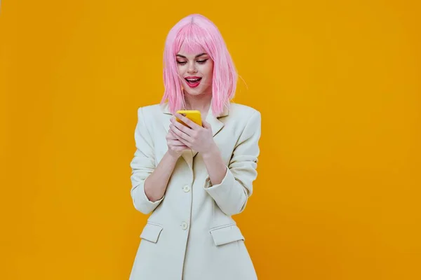 Woman with a phone in her hands pink hair studio yellow background — Stock Photo, Image