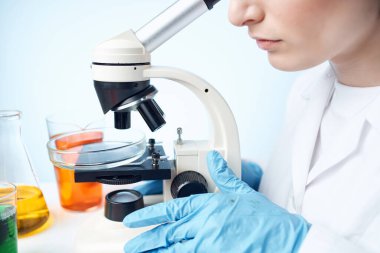 Laboratuvar asistanı mikroskop araştırma stüdyosunda oturuyor.