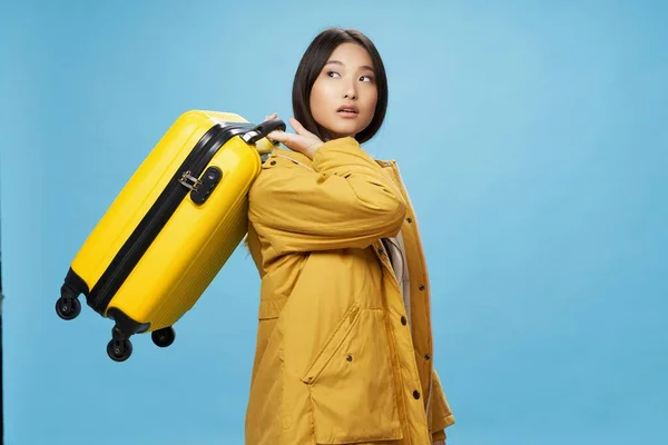 노란 여행 가방을 타고 푸른 배경으로 여행하는 여자 — 스톡 사진