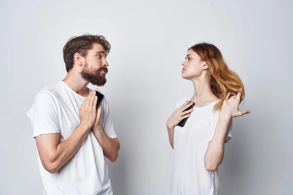 Una familia joven pareja con teléfonos en la comunicación de la mano fondo aislado — Foto de Stock