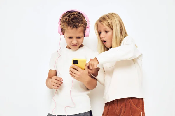 Mladý veselý dítě sluchátka s telefonem zábava světlo pozadí — Stock fotografie