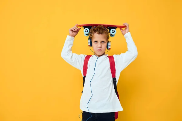Tiener met een rode rugzak dragen skateboard hoofdtelefoon — Stockfoto