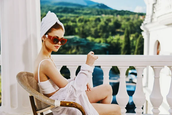 Sensuale e bella donna in occhiali da sole si siede su un balcone aperto concetto di relax — Foto Stock