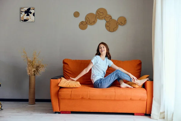 Beautiful woman on the orange couch in the rest room posing unaltered — Stockfoto