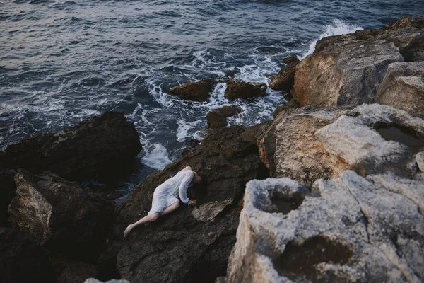 美しい若い女性が岩の多い海岸の景色の上で横になり — ストック写真