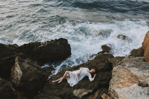 Frau liegt an felsiger Küste mit Rissen auf felsiger Oberfläche Blick von oben — Stockfoto