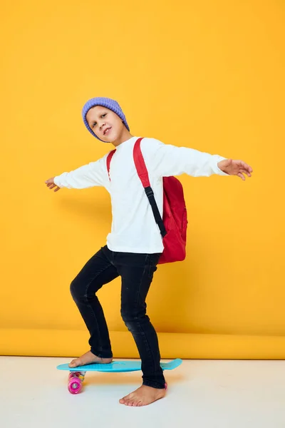 Glad skolpojke i en vit tröja skateboard underhållning gul färg bakgrund — Stockfoto