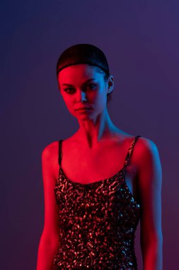 Genç kadın, neon ışıklı arka planda örgü gibi poz veriyor.