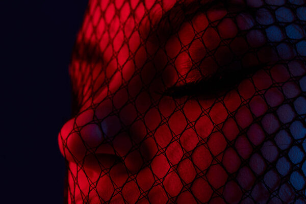 Young woman black veil on the face close-up red light color background. High quality photo
