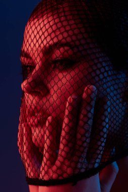 Güzel bir kadın, neon ışıklı arka planda örgü örüyor.