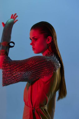 Çekici kadın Glamor elinde değiştirilmemiş kırmızı ışıklı metal zırh poz veriyor.