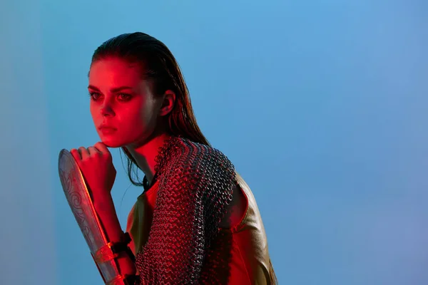 Young woman Glamor posing red light metal armor on hand blue background — Fotografia de Stock