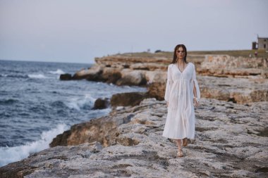 Kadın gezgin adada volkanik kaya oluşumları yürür.