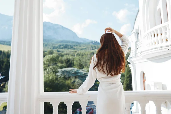Portrait of gorgeous woman looks at a beautiful view from the balcony back view — Fotografia de Stock