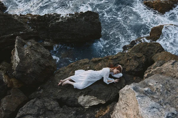 Çıplak ayaklı bir kadın ıssız bir yerde vahşi kayalık bir sahilde, değişmemiş beyaz bir elbiseyle. — Stok fotoğraf