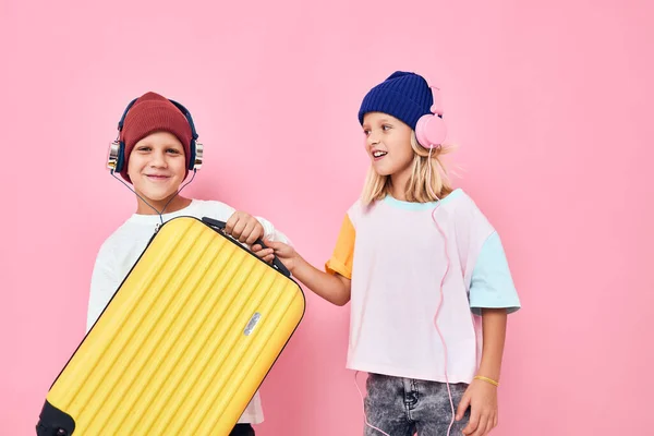 Adorables niños pequeños que se preparan para las vacaciones los viajeros jóvenes de color rosa de fondo —  Fotos de Stock