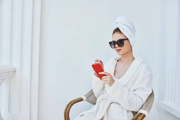 一个身穿白色长袍、拿着手机的女人坐在宾馆的阳台上 — 图库照片