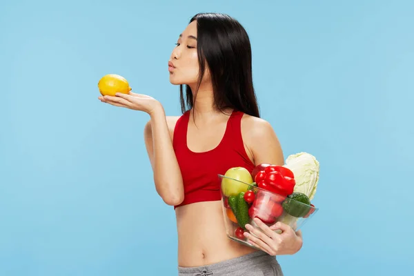 Slim athletic woman with vegetables healthy food blue background — Stockfoto