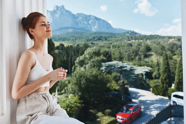 Attractive young woman admires the view of the mountains on the open balcony of the hotel posing — Foto Stock