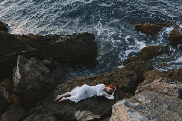 Mujer descalza en un vestido blanco acostada en una piedra en una vista de vestido blanco desde arriba —  Fotos de Stock