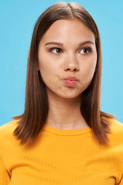 Pretty woman yellow t-shirt face closeup blue background — Foto Stock