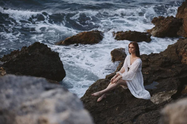 Pretty woman with wet hair in a white dress sits on a cliff nature unaltered — Stock Photo, Image