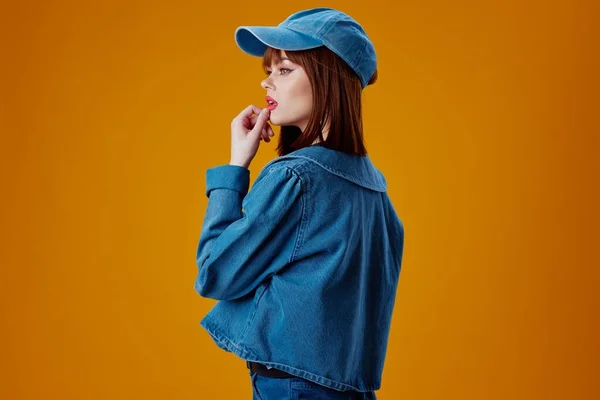 Retrato de una encantadora dama en una gorra y chaqueta de mezclilla posando fondo de color inalterado — Foto de Stock