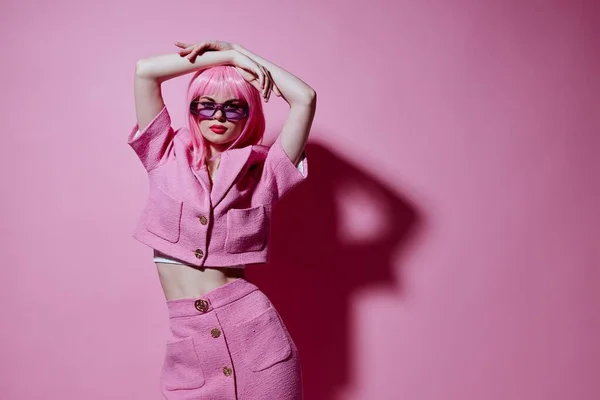 Joven mujer positiva traje rosa gafas de sol posando fondo rosa inalterado — Foto de Stock
