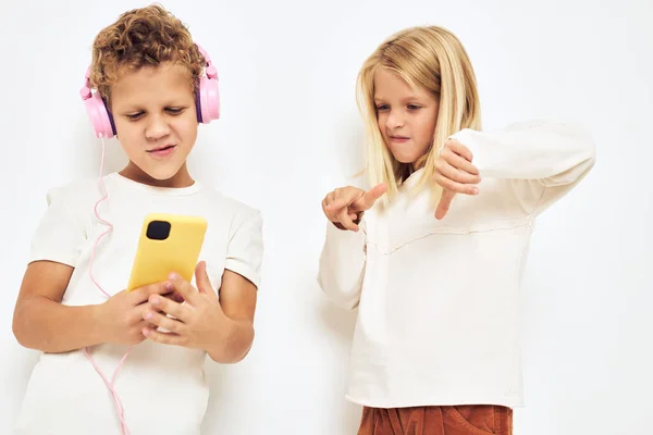 Mladý veselý dítě sluchátka s telefonem zábava izolované pozadí — Stock fotografie