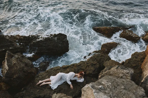 Beautiful woman lying on rocky coast with cracks on rocky surface unaltered — Stock Photo, Image