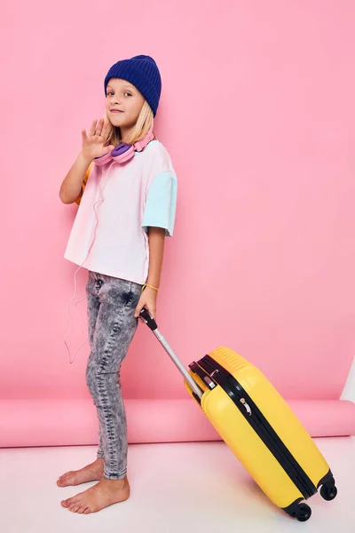 ヘッドフォン付きの女の子黄色のスーツケース旅行子供時代 — ストック写真