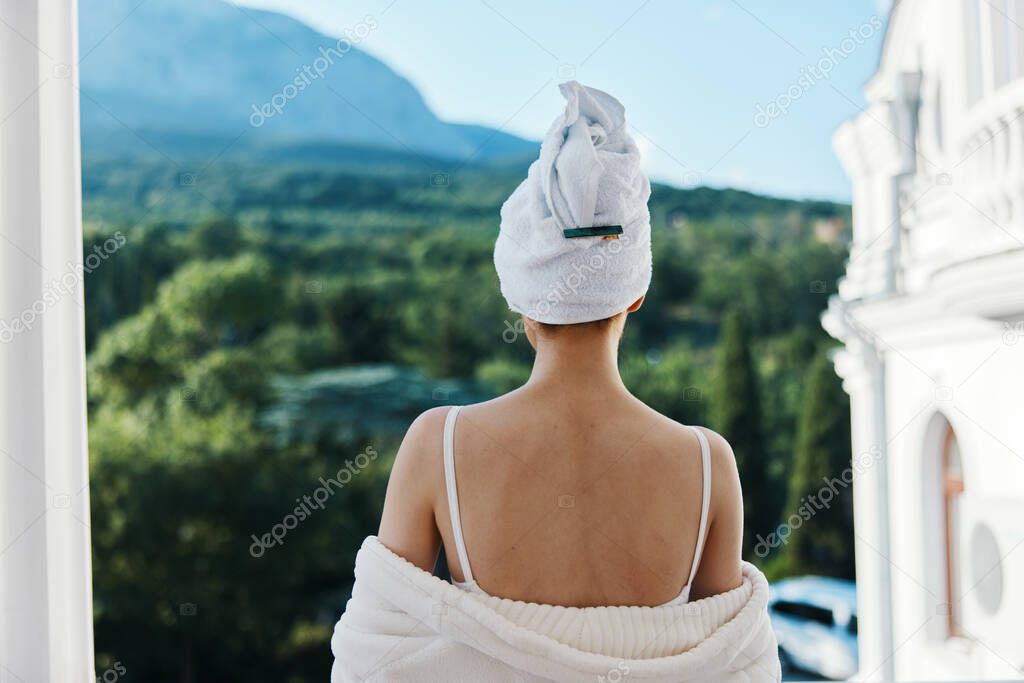 Woman in a bathrobe in a white robe the balcony overlooks the mountains Relaxation concept