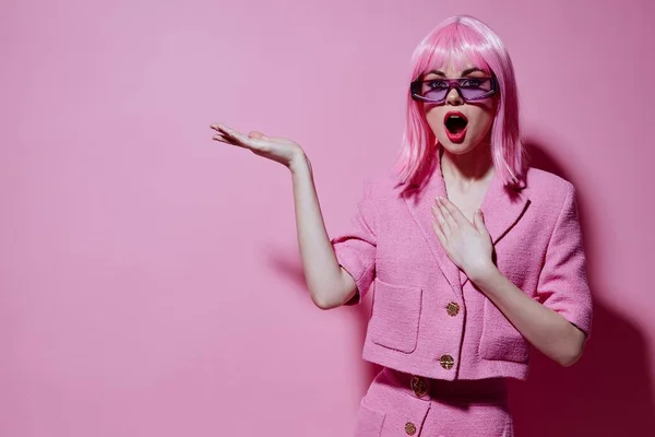 Positivo gesti giovane donna con le mani con una giacca rosa sfondo rosa inalterato — Foto Stock