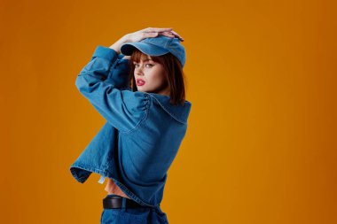 Büyüleyici bir kadın portresi şık bir kot giysisi. Sarı arka plan değiştirilmemiş.