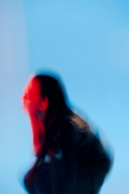 Güzel kadın Glamor elinde mavi arka planda kırmızı ışıklı metal zırh poz veriyor.