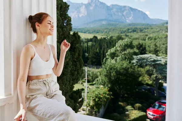매력적 인 젊은 여자 가 호텔의 화창 한 날열린 발코니에 있는 산들의 모습을 감탄하고 있다 — 스톡 사진
