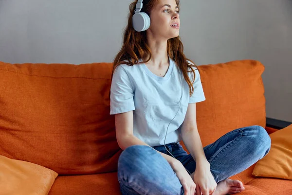 Woman sitting on the couch at home listening to music on headphones apartments — Stock Photo, Image
