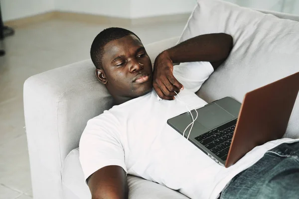 Чоловік африканський зовнішній вигляд вдома на дивані з ноутбуком відпочинок — стокове фото